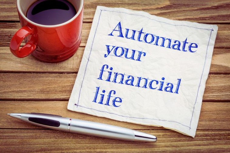 This image includes a cup of coffee and a napkin printed with the message, "Automate your financial life." Doing this is one way to instill financial behavior change.