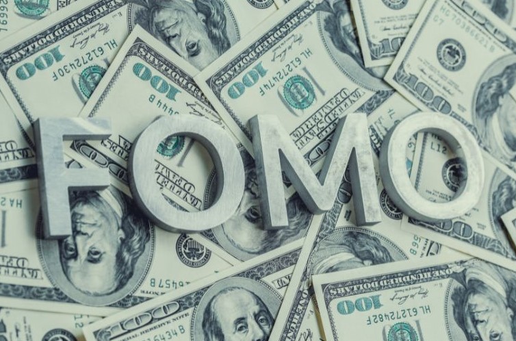 The image shows the acronym "FOMO." Fear of missing out can cause excessive spending. This buying pattern is addressed, in part, through financial behavior change