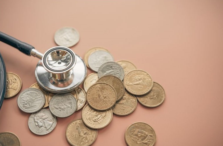 This image shows a stethoscope over coins, symbolizing analyzing our financial health. Holistic financial well-being is achieved, in part, through financial behavior change.